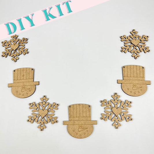 The image showcases the "Snowman and Snowflake Banner" DIY craft kit by Janet's Craft Corner, featuring wooden cutouts in a delightful arrangement. Included are four snowflake shapes and three top hat designs, all embellished with charming heart and button details. Ideal for creating a farmhouse winter decor or a festive snowman banner. The phrase "DIY KIT" is prominently displayed at the top.