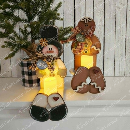 Brighten your holiday decor with Janet’s Craft Corner Snowman & Gingerbread Votive Holder Shelf Sitters DIY home decor craft kit. This set features two charming figurines—a snowman holding a “Snow” sign and a gingerbread person with a “Joy” sign—seated in front of a plaid pot topped with a pine tree, all against a rustic white wooden wall. Perfect for adding festive warmth and cheer to any space, these delightful shelf sitters make an inviting addition to your Christmas home decor.