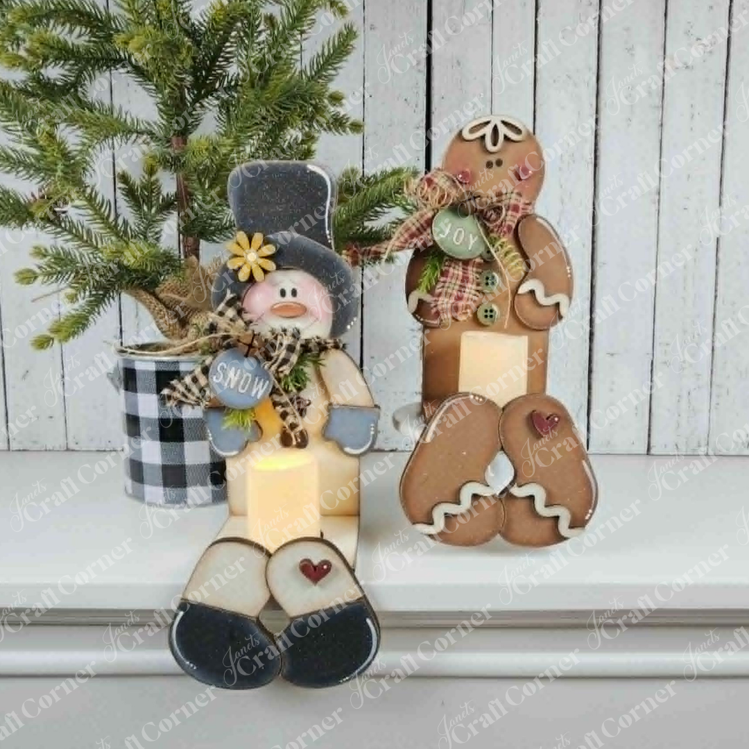 Add a cheerful holiday accent to your space with the Snowman & Gingerbread Votive Holder Shelf Sitters DIY home decor craft kit by Janet’s Craft Corner. Displayed on a white shelf, these festive figures—adorned with winter accessories—are paired with a small potted pine tree in a black-and-white plaid pot. The charming arrangement of this craft kit brings inviting Christmas home decor and cozy seasonal spirit to your room.