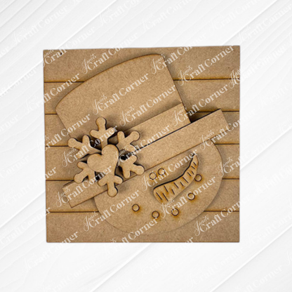 The Snow Squares from Janet's Craft Corner feature a snowman face cutout with a carrot nose, smile, heart-accented snowflake, and pair perfectly with swappable signs for festive DIY home decor.
