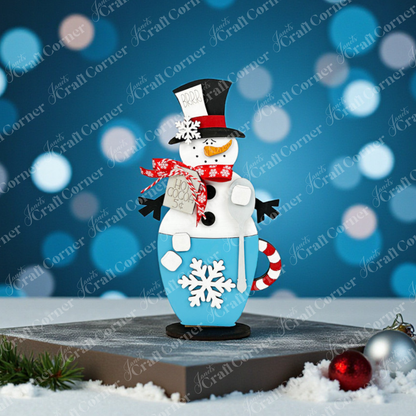 Decorate your home with the Snowman Hot Cocoa Mug Shelf Sitter by Janet's Craft Corner, showcasing a festive snowman sporting a black top hat, red scarf, and carrot nose in a blue mug adorned with a white snowflake. This delightful DIY kit is accentuated with marshmallows and a candy cane for the perfect holiday touch.