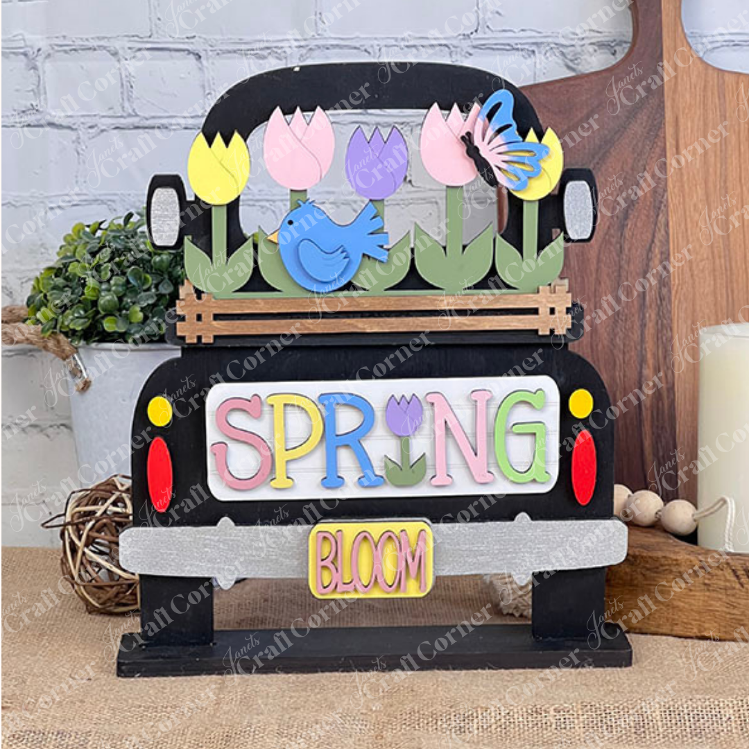 A delightful DIY décor from Janet's Craft Corner, this Antique Truck Base features colorful tulips, a bird, and a butterfly. "SPRING" is hand-painted with the "I" as a tulip in pastel colors, while "BLOOM" decorates the license plate for charming rustic elegance.