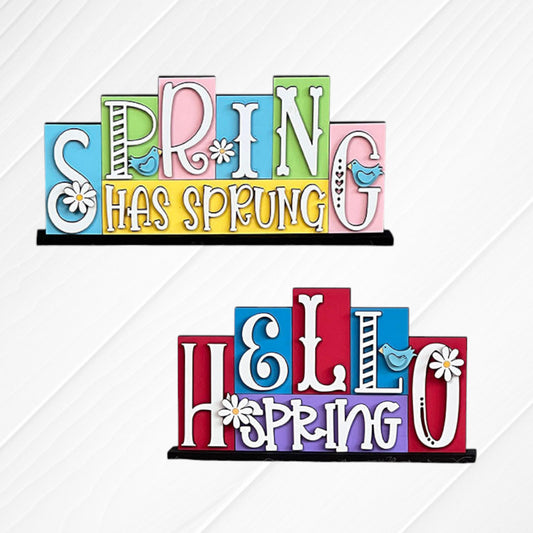 Brighten your home with Heartland's Spring Mini Word Block Shelf Sitters—painted pastel blocks featuring playful fonts, daisy accents, blue birds, and cheerful phrases like "Spring Has Sprung" and "Hello Spring." Perfect spring decor!.