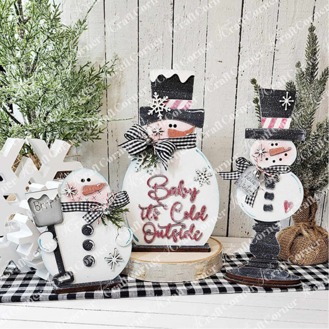 The Snowman Mini Shelf Sitter from Janet's Craft Corner is a DIY seasonal home decor craft kit featuring a snowman with a hat, scarf, and rosy cheeks. A white wooden tree and greenery add festive charm to your holiday display. Set of 1.