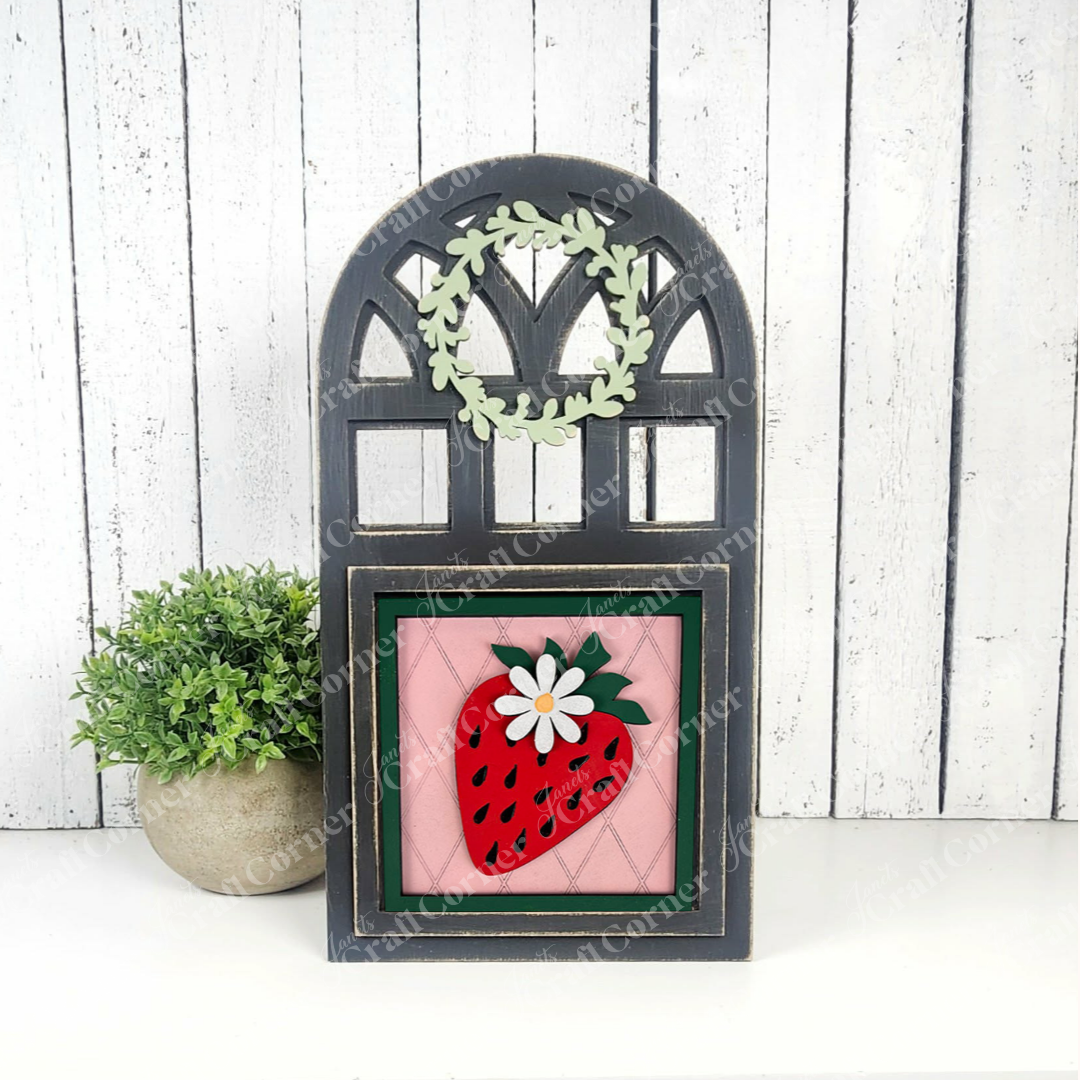 Janet's Craft Corner’s DIY Strawberry Swappable Squares kit pairs a pink sign with a red strawberry and white flower, an arched black window frame with green wreath, and a potted plant—ideal for seasonal or tiered tray decor.