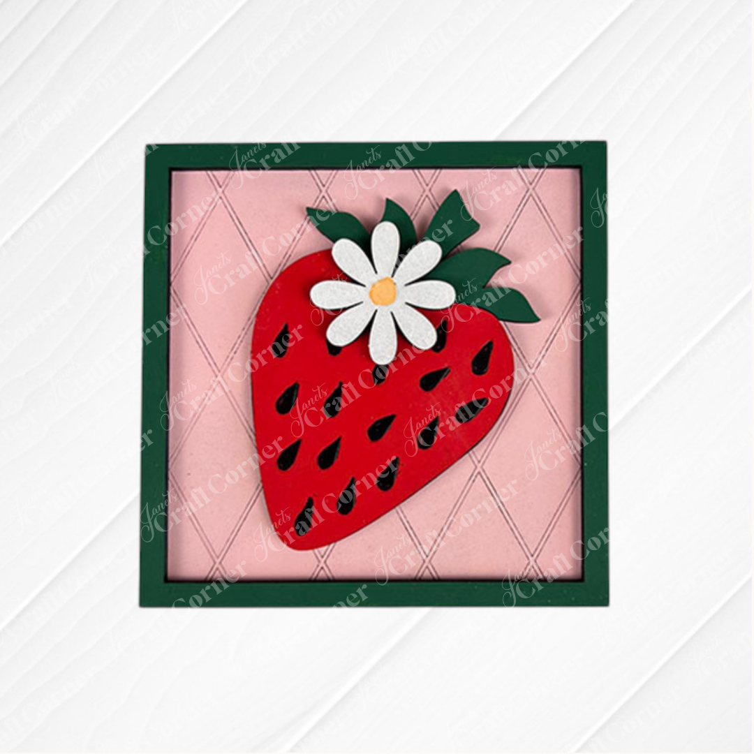 The Strawberry Swappable Squares DIY craft kit by Janet's Craft Corner features a square red strawberry with black seeds and a white daisy on pink quilted background in a dark green frame—ideal for seasonal tiered tray decor.