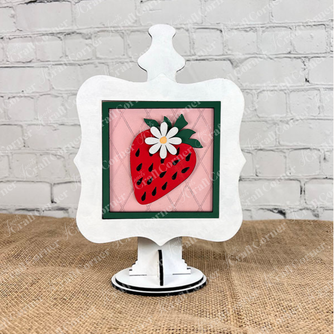 Janet's Craft Corner presents the Strawberry Swappable Squares DIY seasonal home decor craft kit—framed art with a strawberry, white flower, and green leaves on a decorative easel, ideal for tiered tray displays.