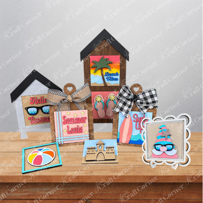 The Summer Lovin Swappable Squares DIY craft kit from Janet's Craft Corner features wooden cut-outs like beach huts, sunglasses, flip-flops, a sandcastle, and a beach ball—perfect for summer-themed tiered tray decor.