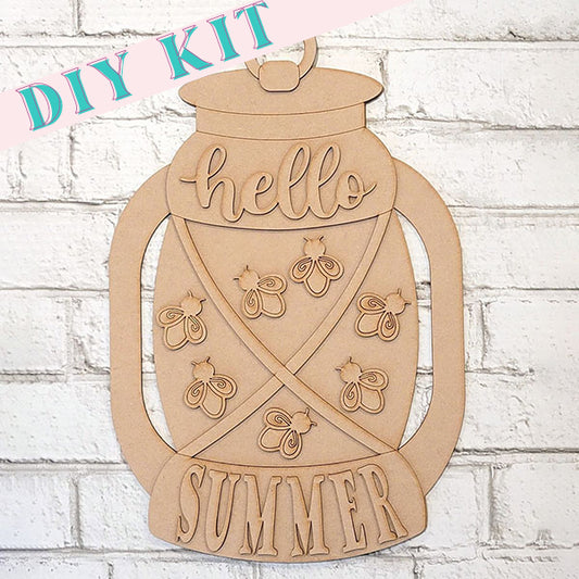 The Summer Lantern Door Hanger from Janet's Craft Corner is a delightful wooden DIY kit that perfectly complements farmhouse-style home decor. Featuring the phrase "hello SUMMER" and adorned with firefly designs, this piece makes a charming addition to any door. Positioned against a light brick wall, it showcases a banner in pink and blue at the top left corner reading "DIY KIT.