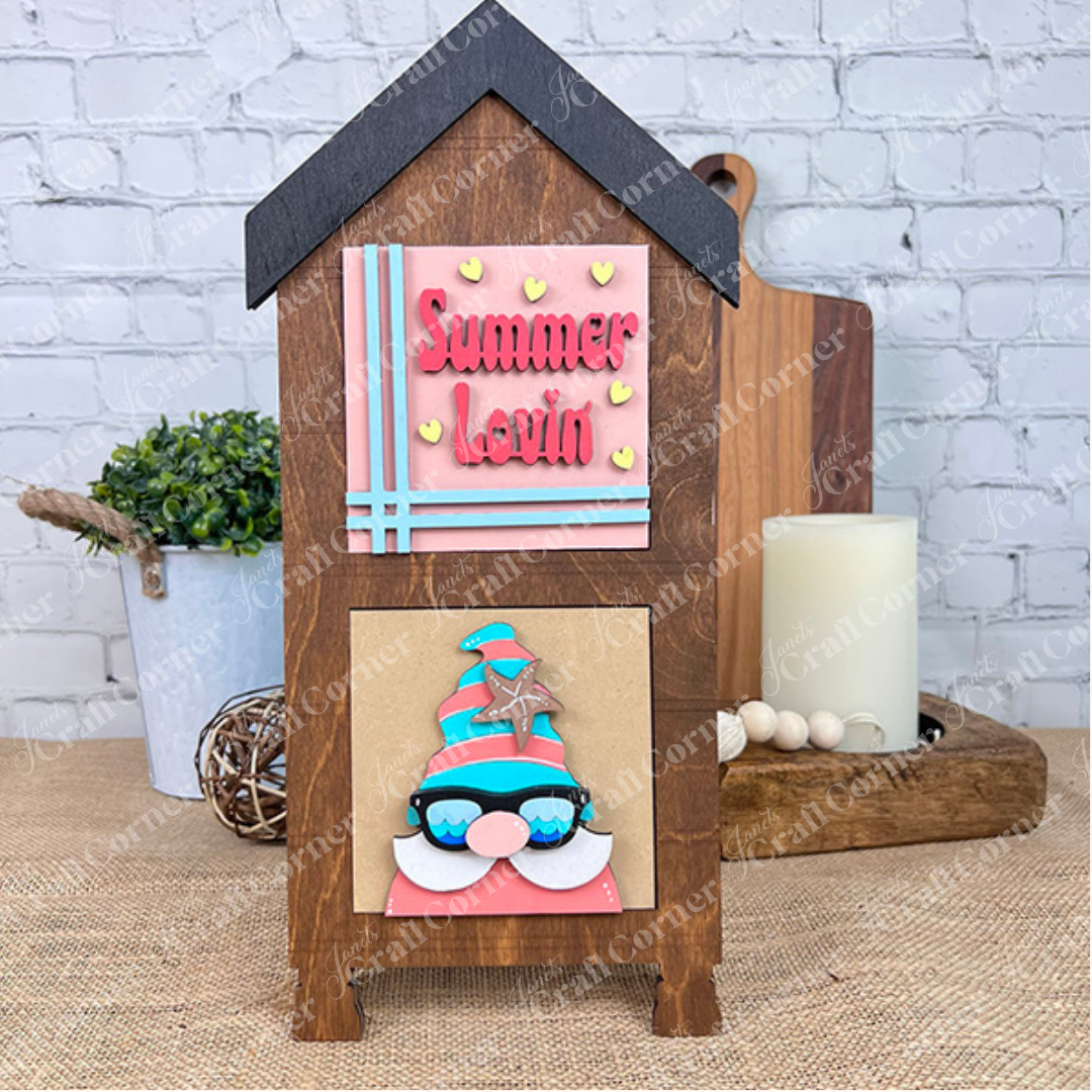 The Summer Lovin Swappable Squares DIY craft kit from Janet's Craft Corner features a house-shaped wooden piece with a gnome in sunglasses—perfect for tiered trays and seasonal home decor to brighten any space.