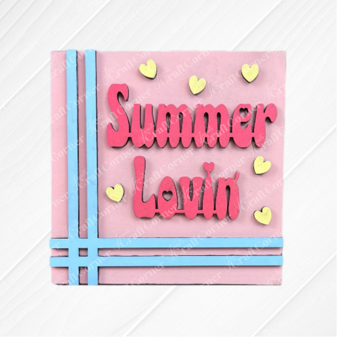 The "Summer Lovin Swappable Squares" DIY craft kit from Janet's Craft Corner features a pink square card with light blue striped edges and bold pink "Summer Lovin" text, accented by yellow hearts—ideal for seasonal home decor.