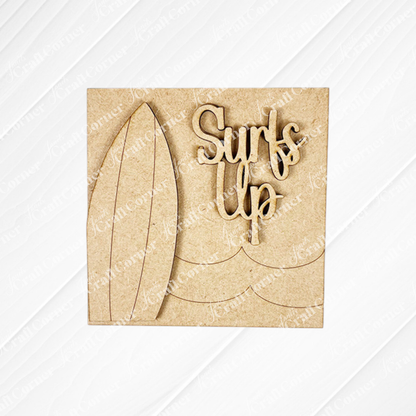 The Summer Beach Squares DIY craft kit from Janet's Craft Corner features a wooden cutout with a surfboard, wavy sea lines, and "Surf's Up" in playful font—ideal as tiered tray signs or coffee bar decor, set on light wood with subtle diagonal texture.