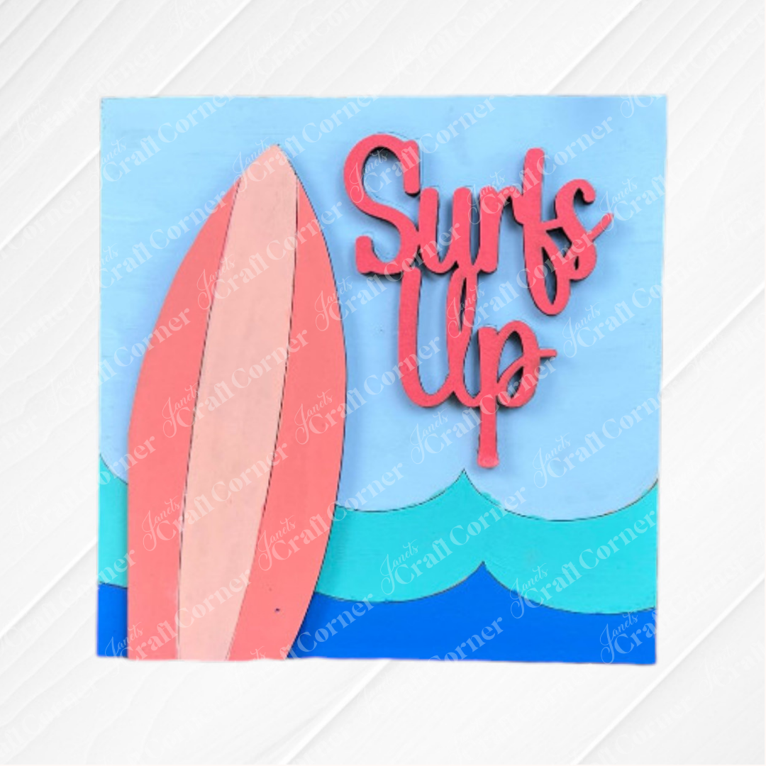 A colorful illustration from Janet's Craft Corner's Summer Beach Squares DIY kit shows a pink surfboard and blue waves with bold "Surf's Up"—ideal as a wood cut-out for tiered tray signs or bright small space decor.