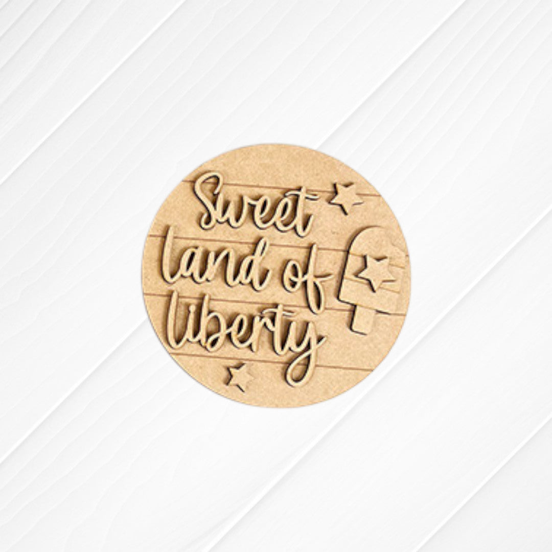 Janet's Craft Corner Patriotic Mini Shelf Sitters DIY Craft Kit features a round wooden sign with “Sweet land of liberty” in cursive, stars, and a popsicle—ideal for Americana décor or as festive accents on any shelf.