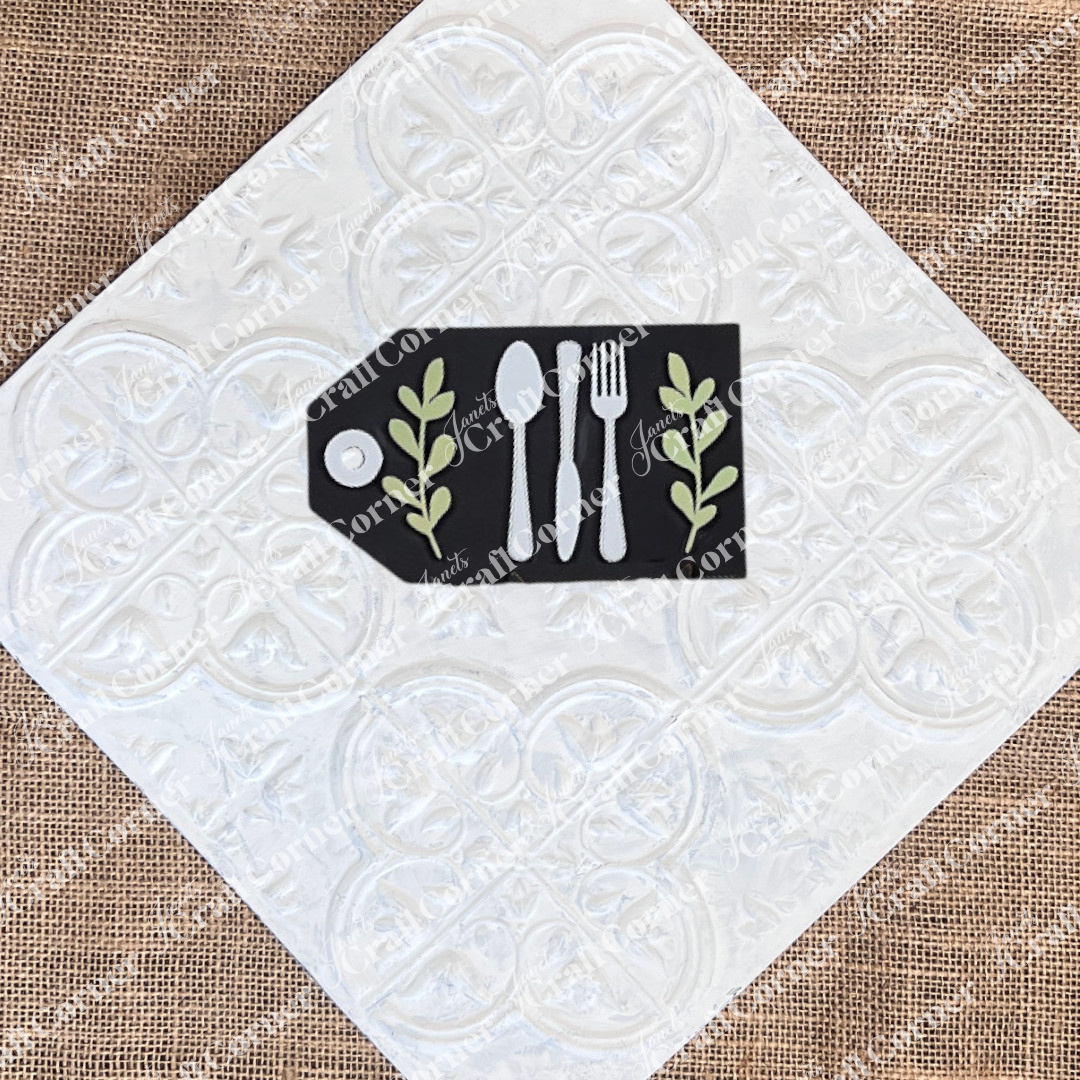 The "Thankful Mini Shelf Sitters" DIY craft kit by Janet's Craft Corner features a small black board with fork, knife, and spoon illustrations and green leaf accents—perfect for creating unique seasonal home decor.