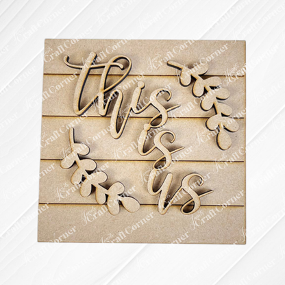 The Family Home Squares by Janet's Craft Corner features "this is us" in cursive with leaf accents and wood cut-outs on a wooden plank backdrop—ideal for tiered tray decor.