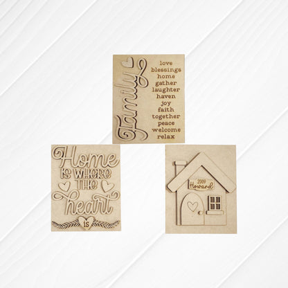 The Family-Home Switchable Farmhouse Sign by Janet's Craft Corner is a DIY home decor kit featuring "Family" with a heart, "Home is where the heart is," and a house labeled "2009 Howard" on white textured plaques. Set of 1.