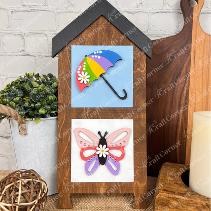 Janet's Craft Corner's Hello Spring Squares features a wooden house-shaped frame with two swappable tiles—a colorful umbrella and a pink and purple butterfly—perfect for brightening your tiered tray décor.