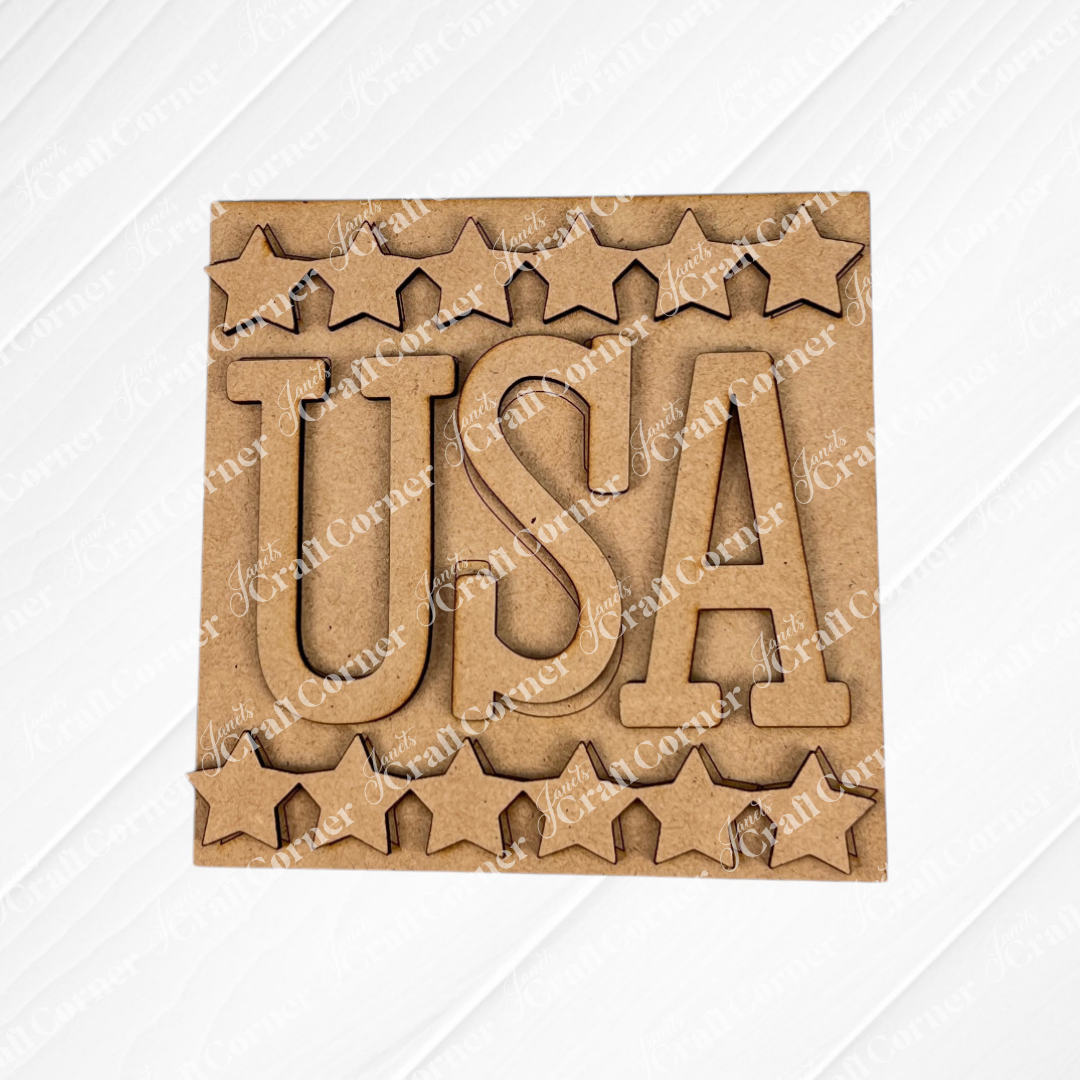 Janet's Craft Corner presents the Patriotic Squares DIY seasonal home decor kit—a square wooden cutout with bold "USA" in the center, star-shaped edges, and a plain white background, ideal for your Independence Day decorations.