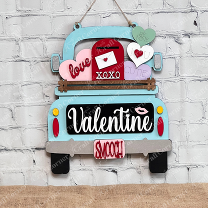 Janet's Craft Corner offers the Valentine Interchangeable Insert DIY home decor kit, a decorative wooden sign shaped like a vintage truck with hearts and an envelope, featuring words like "love," "XOXO," and "cutie." Ideal for Valentine's Day, it hangs beautifully on a white brick wall.