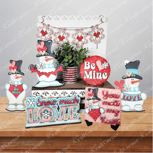 Janet’s Craft Corner Valentine Snowmen Decor Set is a DIY kit with wood cut-outs of snowmen, hearts, potted plants, and signs like “Be Mine” and “You melt my heart” in red, pink, blue, and white—perfect for charming Valentine’s Day decor.