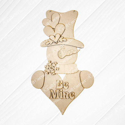 Janet's Craft Corner Valentine Snowman Door Hanger DIY kit includes a plain, unfinished wooden snowman with hat, scarf, heart body reading "Be Mine," and a snowflake—perfect for personalizing your seasonal home decor. Set of 1.