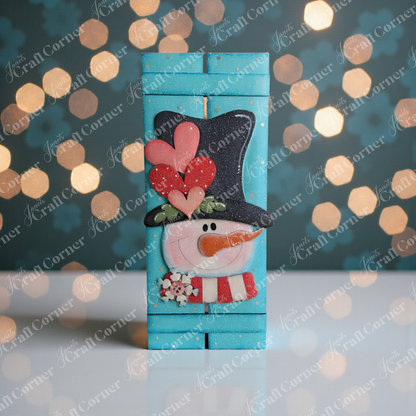 Janet's Craft Corner Valentine Snowman Table Top Pallet Shelf Leaner is a DIY winter décor kit featuring a cheerful snowman with a carrot nose, black hat with hearts, and festive blue bokeh background. Set of 1.