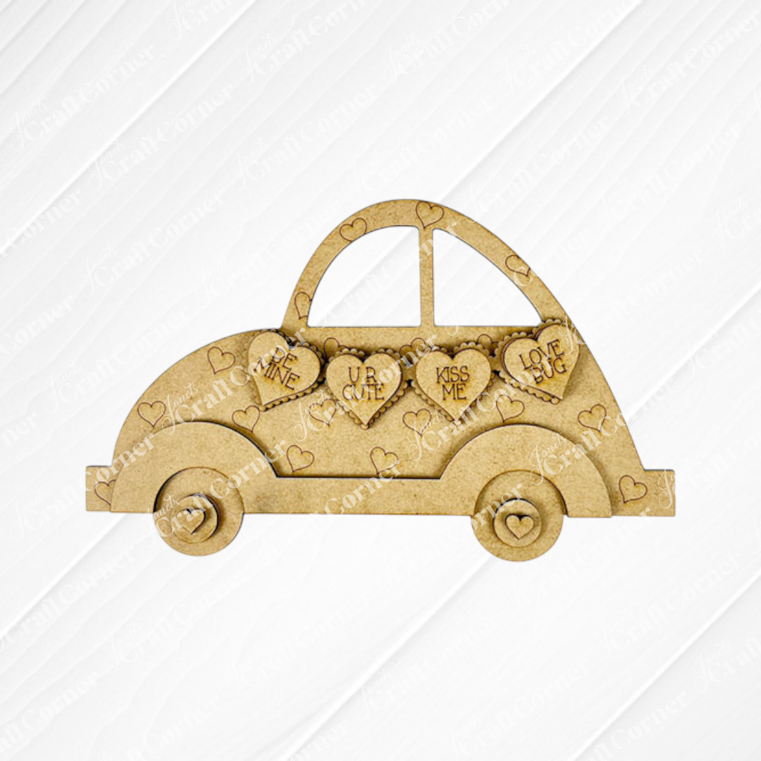 Janet's Craft Corner offers a Valentine Volkswagen Shelf Sitter DIY kit, featuring a vintage-style car adorned with heart shapes, some engraved with messages like "BE MINE" and "KISS ME," adding charm to this seasonal home decor.