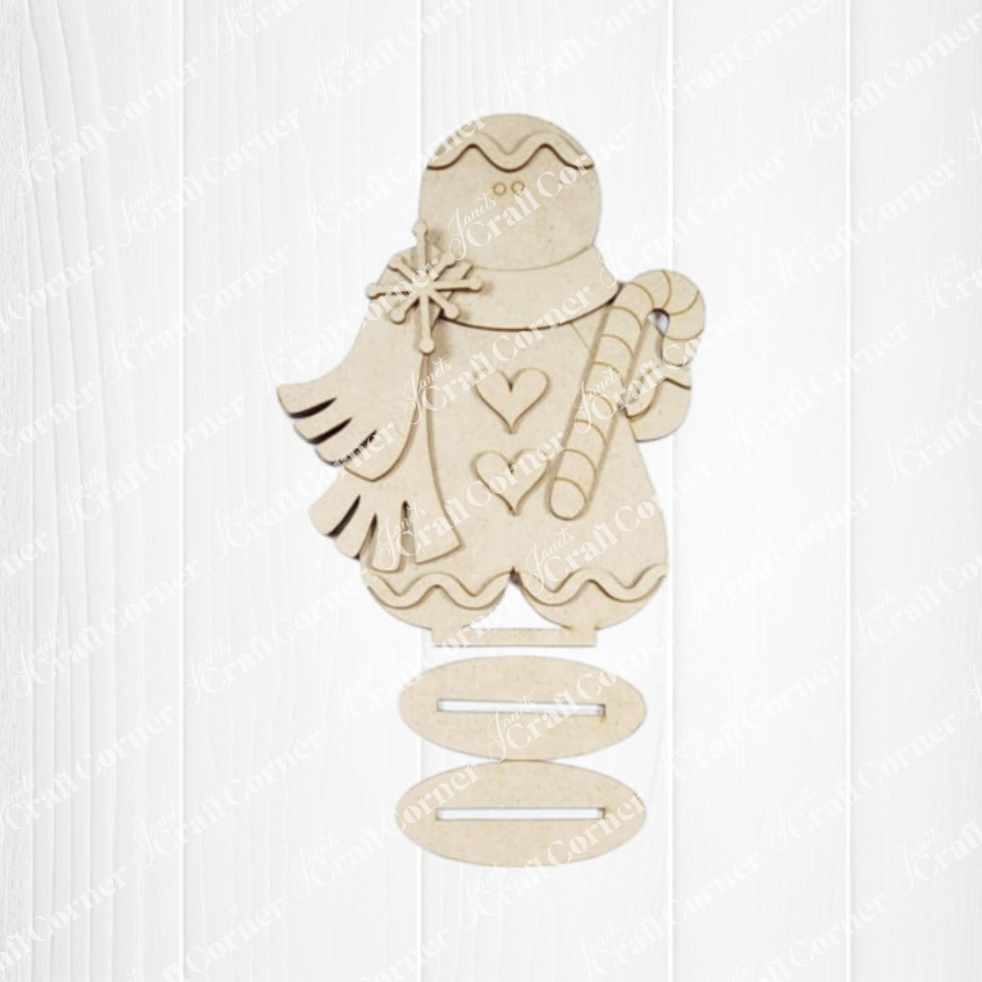 Display Janet’s Craft Corner Gingerbread Mini Shelf Sitters—a DIY seasonal home decor kit—against a white wood background, or pair it with a wooden angel cutout for festive holiday decorating. Set includes 1 piece.