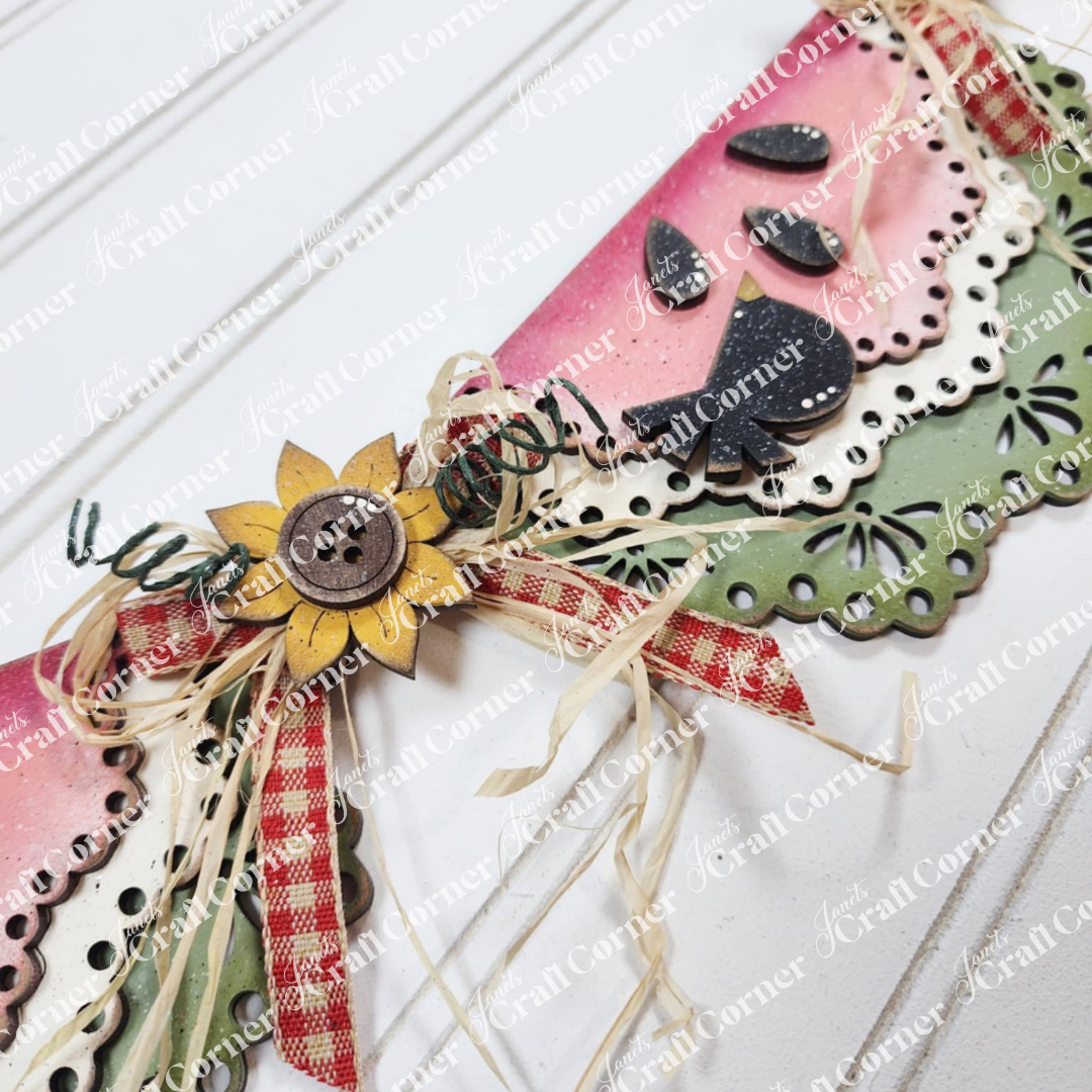 Janet's Craft Corner's 1a - MASTER product is a handmade paper decoration featuring a watermelon slice, sunflower, wood cut-outs, button, raffia bow, and gingham ribbon—ideal for DIY seasonal home decor.