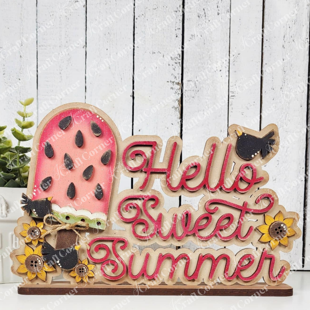 The Vintage Watermelon Word Art Shelf Sitter by Janet's Craft Corner features "Hello Sweet Summer" in pink cursive with sunflowers on a white wooden background, adding a cheerful touch to your home decor.