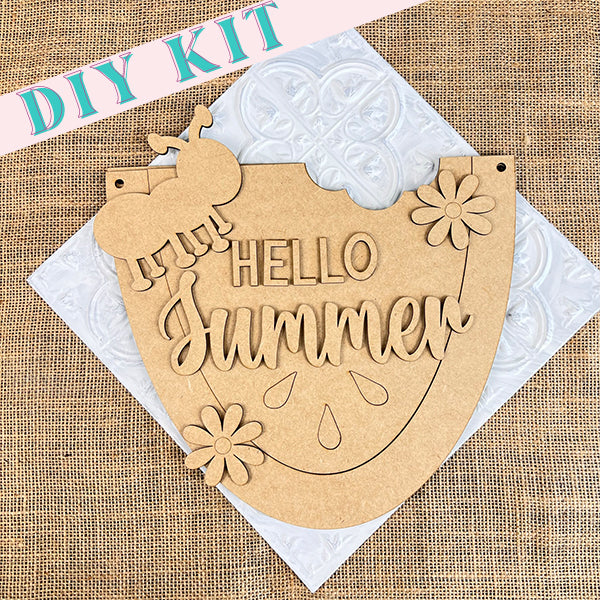 The "Hello Summer Watermelon Door Hanger" from Janet's Craft Corner is a DIY kit ideal for summer décor. It features a wooden sign with a design of a bitten watermelon slice, flowers, and an ant. The decorative white embossed pattern on the burlap texture adds to its charm.