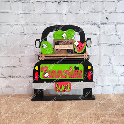 The Summertime Watermelon Interchangeable Insert - Painted, by Janet's Craft Corner, showcases a charming black truck with hand-painted ornaments of watermelons and daisies in the back. The tailgate is adorned with the words "Summertime" and "Sweet." An accompanying small wooden crate labeled "Watermelons," surrounded by polka dots and black cat silhouettes, adds interchangeable home decor charm.