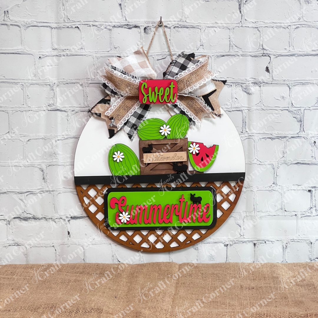 Introducing the **Summertime Watermelon Interchangeable Insert - Painted** by *Janet's Craft Corner*: This hand-painted decoration on a white door hanger base showcases watermelons and a watermelon slice, paired with a green "Summertime" sign. Enhanced with black silhouettes of ants and white daisy flowers, this charming piece is perfect for your home decor.