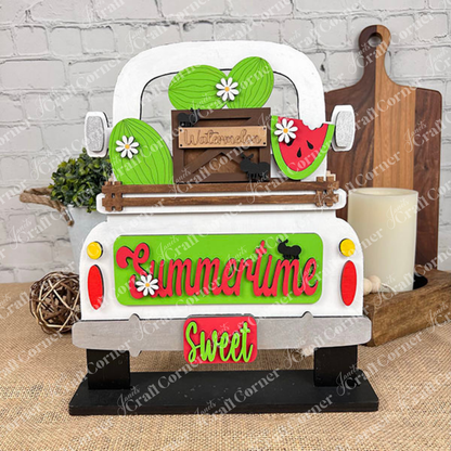 The Summertime Watermelon Interchangeable Insert - Painted, by Janet's Craft Corner, showcases a charming white truck with hand-painted ornaments of watermelons and daisies in the back. The tailgate is adorned with the words "Summertime" and "Sweet." An accompanying small wooden crate labeled "Watermelons," surrounded by polka dots and black cat silhouettes, adds interchangeable home decor charm.