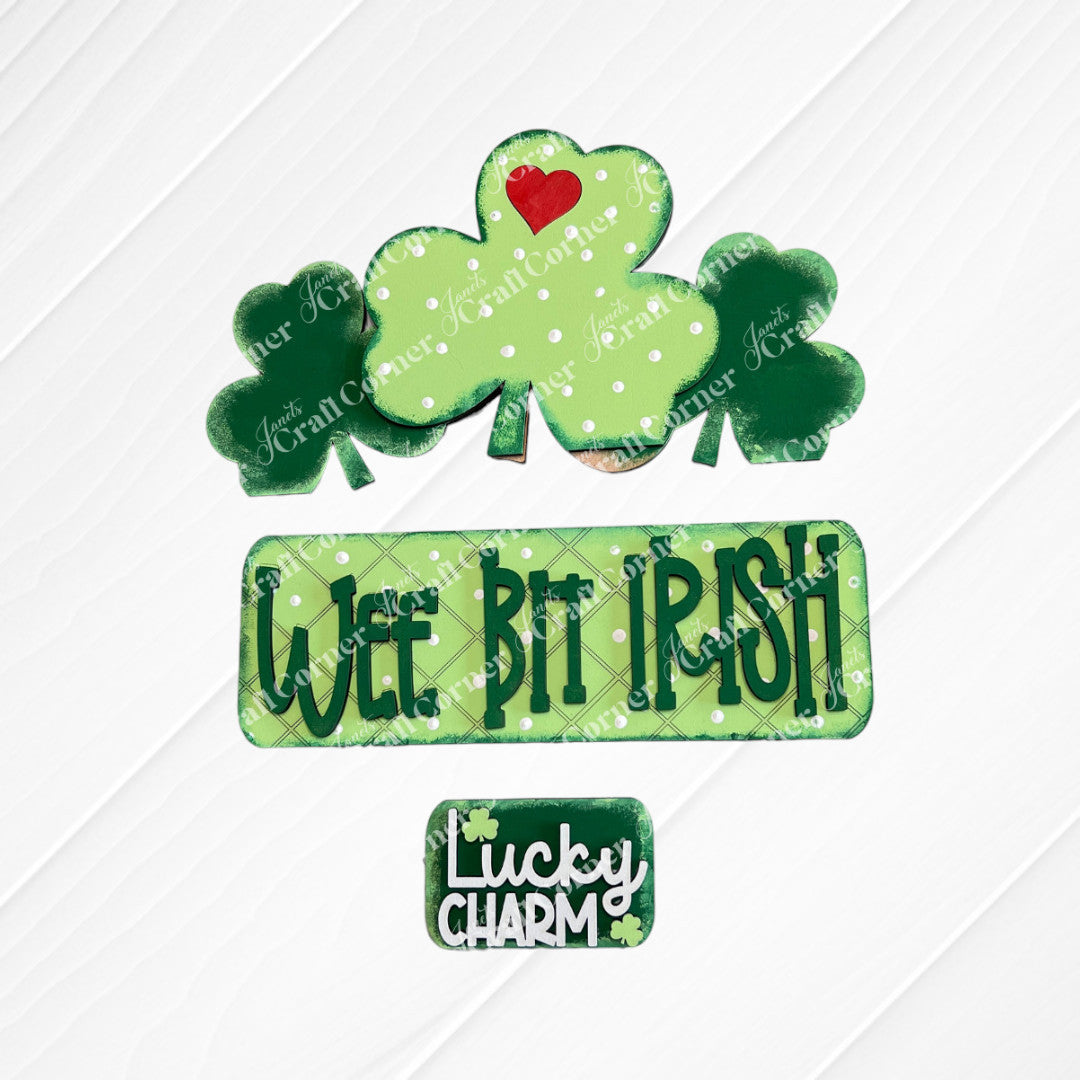 The "Wee Bit Irish Interchangeable Insert" by Janet's Craft Corner features cookies with green shamrocks and a red heart, ideal for displaying Irish pride. Text cookies say "Wee Bit Irish" and "Lucky Charm" on a burlap backdrop.