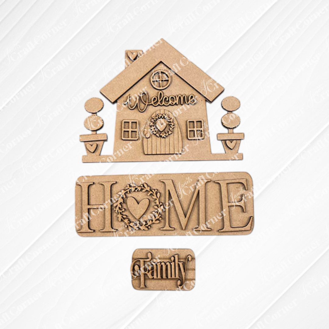 The "Welcome Home Interchangeable Insert" from Janet's Craft Corner is a DIY home decor kit that includes wooden cutouts of a house with signs reading "Welcome," "Home," and "Family." This charming piece features hand-painted details on a white textured square overlaying burlap fabric, with a heart wreath accenting the "Home" sign.