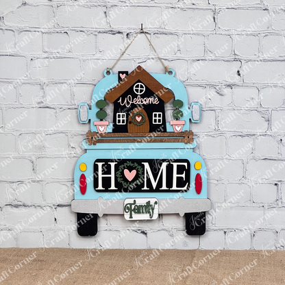 Janet's Craft Corner presents the "Welcome Home Interchangeable Insert" DIY kit. This set includes a blue truck sign with a house and "Welcome" sign, featuring "HOME" on the tailgate with a heart-shaped "O," and a mini family sign, ideal for an inviting farmhouse decor against white brick walls.
