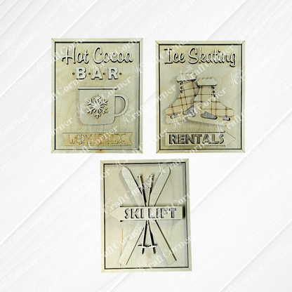 The "Winter Ski Lodge Interchangeable Signs" by Janet's Craft Corner are rustic wooden pieces, showcasing a hot cocoa bar, ice skating rentals, and a ski lift sign with crossed skis all on a white wood background.