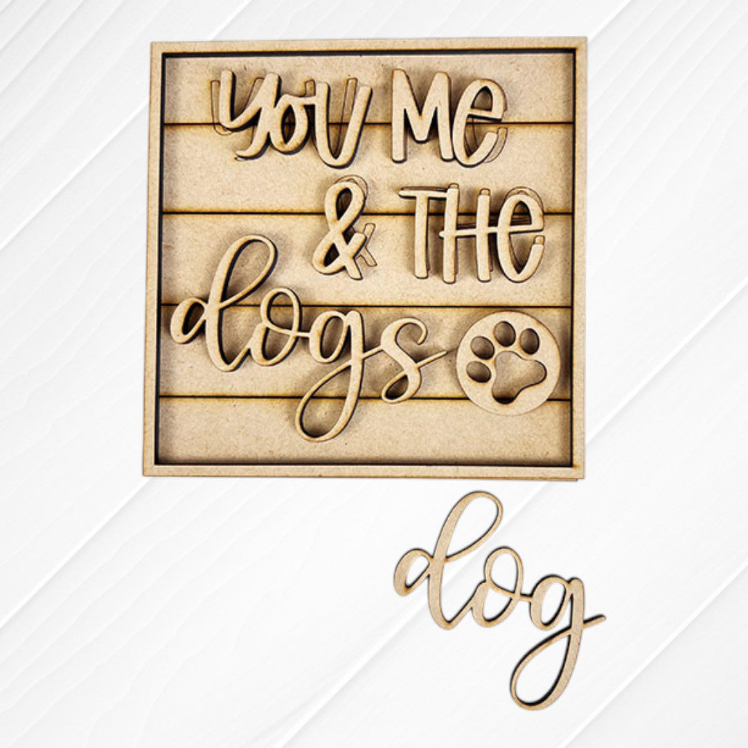 Janet's Craft Corner Dog Squares: Wooden cutout sign says "You Me & The Dogs" with a paw print. Features wood accents on a slatted background and "dog" displayed below on a white surface—perfect for tiered tray decor.