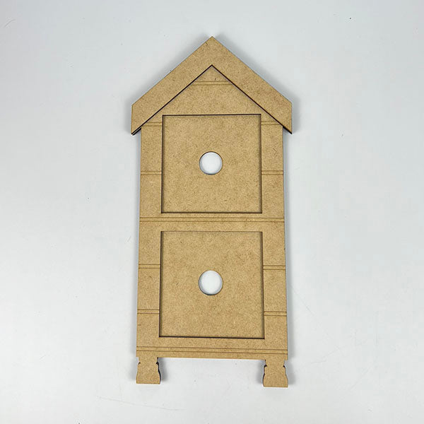 This delightful piece from Janet's Craft Corner, known as the House Interchangeable Squares Holders, is ideal for farmhouse décor aficionados. It mimics a quaint two-story structure with a triangular roof and features two circular cutouts on each level. Placed against a simple white backdrop, it introduces rustic charm to any setting.