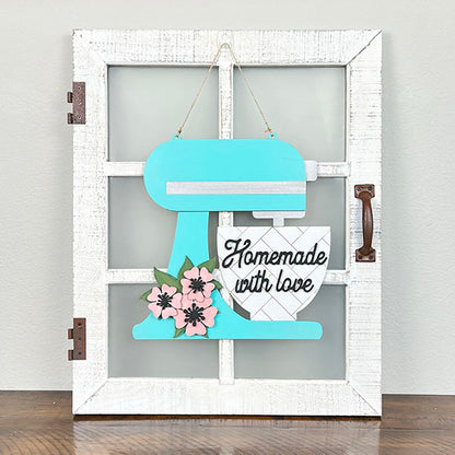 Introducing the delightful Kitchen Mixer Wall Hanger from Janet's Craft Corner. This charming home decor piece features a teal stand mixer cutout set against a white farmhouse-style window frame. Decorated with a heart and pink flowers, it is beautifully complemented by the words "Homemade with love," adding an inviting touch to any space.