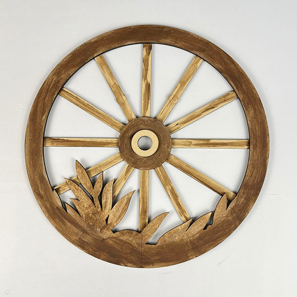 The Interchangeable Wagon Wheel Door/Wall Hanger by Janet's Craft Corner features a wooden wheel with a cut-out design, showcasing a circle of spokes and intricate leaf carvings at the base. It's an elegant addition to your home décor, making a striking impression against a plain white background.