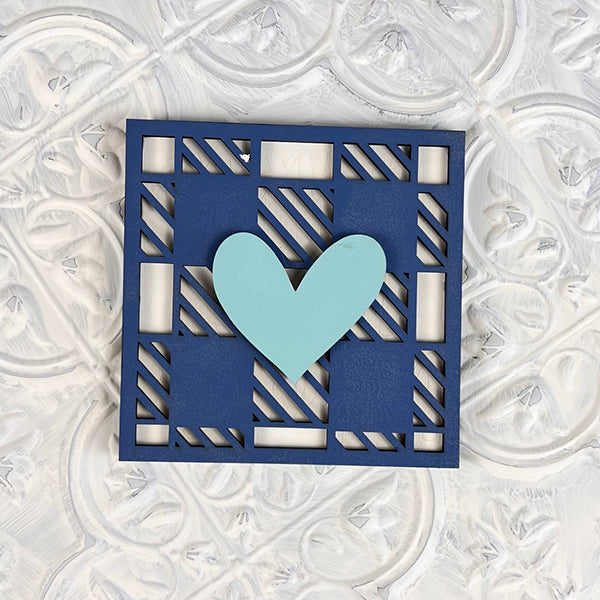 A delightful piece from Janet's Craft Corner, the Home Family Interchangeable Squares features a charming decorative square card. It showcases a grid overlay in blue with a central light blue heart, set against an intricate textured background of swirling patterns in white and gray tones. This makes it an ideal addition for versatile mini signs.